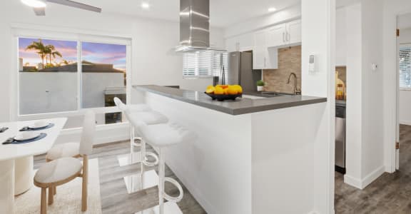 a white kitchen with a bar and a dining area
