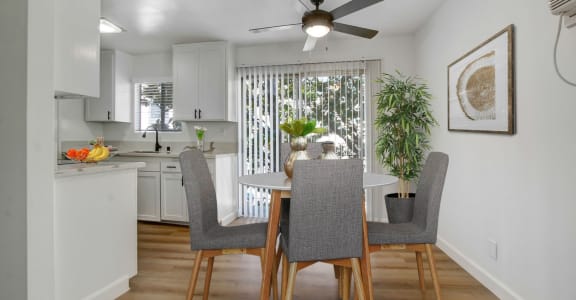 a dining area with a table and chairs and a ceiling fan