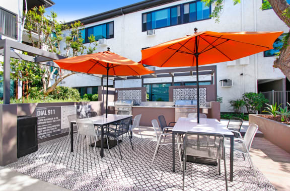 a patio with orange umbrellas and tables outside of a building