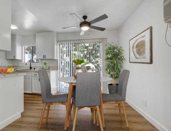 a dining area with a table and chairs and a ceiling fan