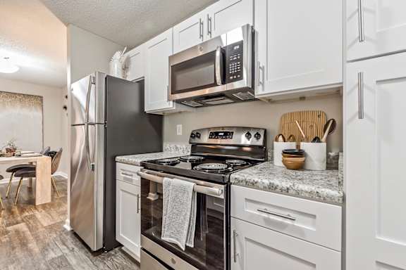 an updated kitchen with stainless steel appliances and white cabinets