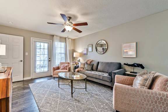 a living room with couches and chairs and a ceiling fan