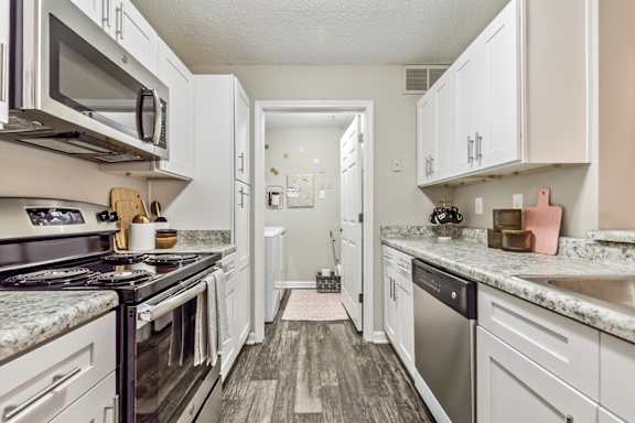 a kitchen with white cabinets and stainless steel appliances