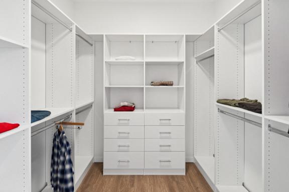A white walk in closet with drawers and shelves.