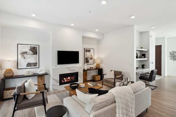 A modern living room with a fireplace and a grey couch.