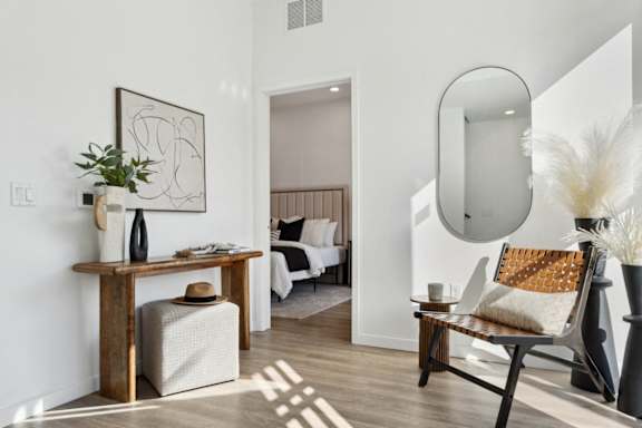 A modern living room with a wooden table and a large mirror on the wall.