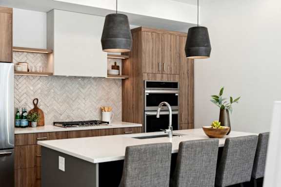 A modern kitchen with a white countertop and grey chairs.