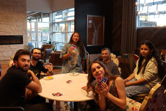 A group of people are sitting around a table playing a card game.