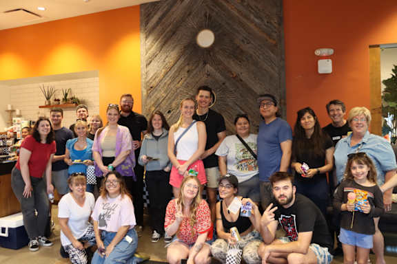 A group of people posing for a photo in a room with a wooden wall.