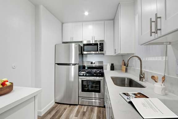A modern kitchen with stainless steel appliances and white cabinetry.