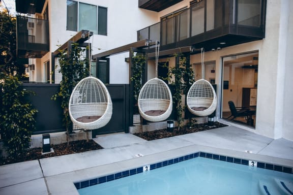 Pool with an outdoor hanging rattan egg chairs