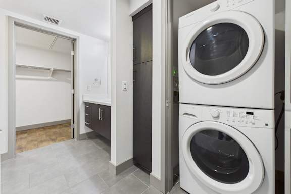 A white washing machine is in a laundry room with a dryer next to it.