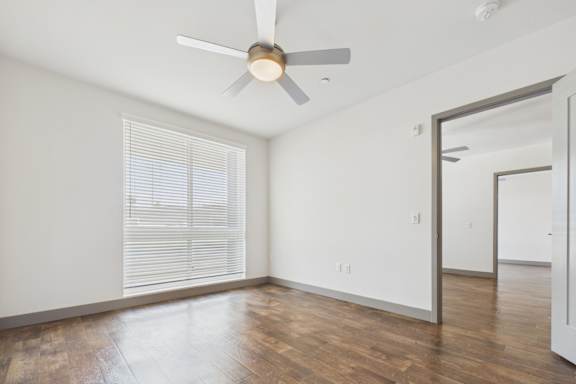 A room with a ceiling fan and wooden flooring.