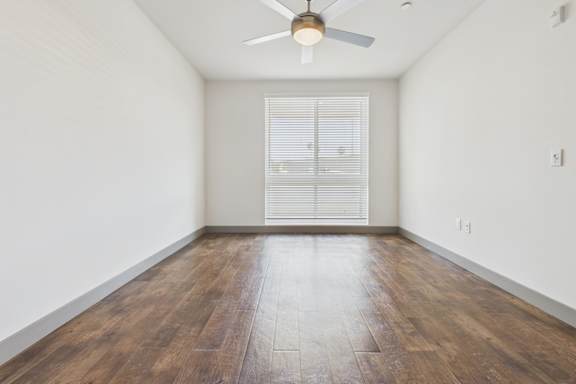 A room with wooden flooring and a ceiling fan.