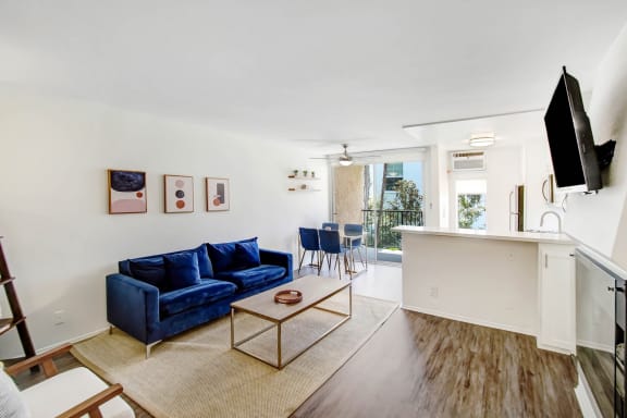 a living room with a blue couch and a kitchen with a table and chairs