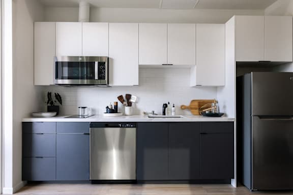 A modern kitchen with a white countertop and a white sofa in the living room.at Skylar At Sunset, Los Angeles