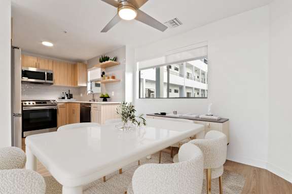 A modern kitchen with a white dining table and chairs.