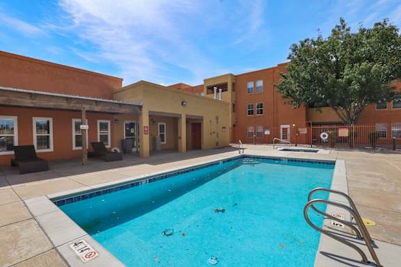 A pool in front of a building with a tree.