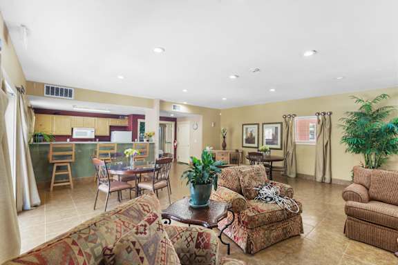 A living room with a couch, chairs, and a dining table.