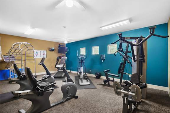 A gym with exercise equipment and a blue wall.