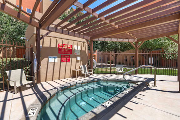 A pool with a wooden pergola over it.