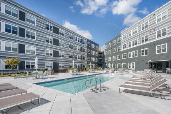 an apartment building with a swimming pool and lounge chairs