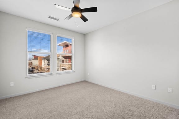 a bedroom with two windows and a ceiling fan