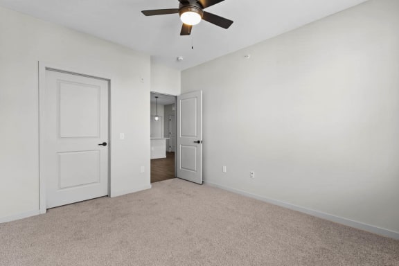 a bedroom with white walls and a ceiling fan