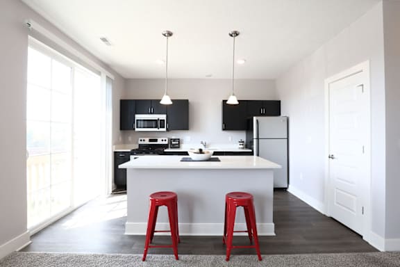 a kitchen with red stools and a white counter top