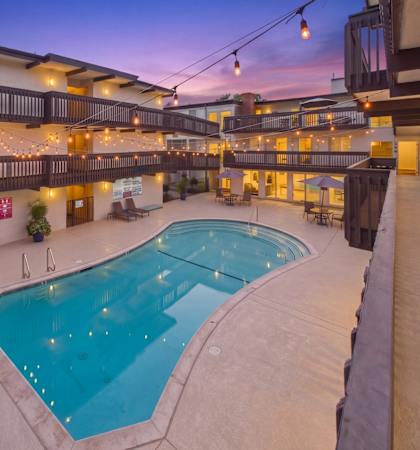 A large outdoor swimming pool surrounded by a patio area with lights strung above.