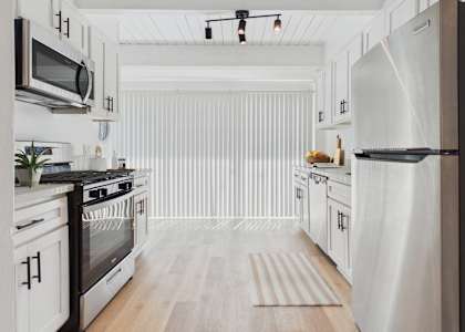 A modern kitchen with black and white appliances and wooden floors.