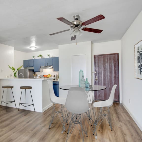 a dining area with a table and chairs and a kitchen in the background