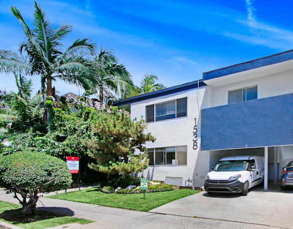a white building with a blue roof and palm trees in front of it