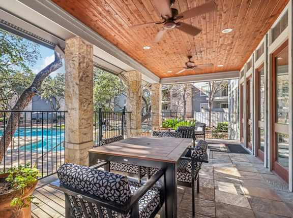 A patio with a table and chairs overlooking a pool.