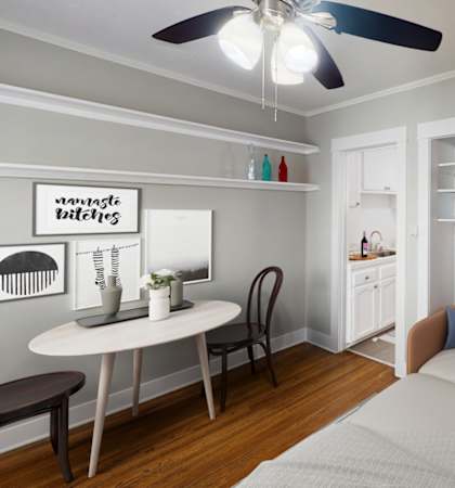 A bedroom with a bed, a table, and a ceiling fan.