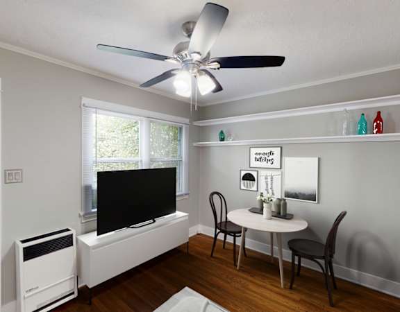 A room with a ceiling fan, a table with chairs, and a window.