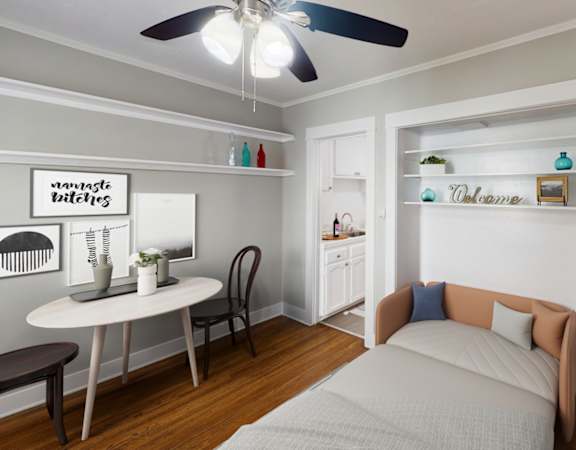 A bedroom with a bed, a table, and a ceiling fan.