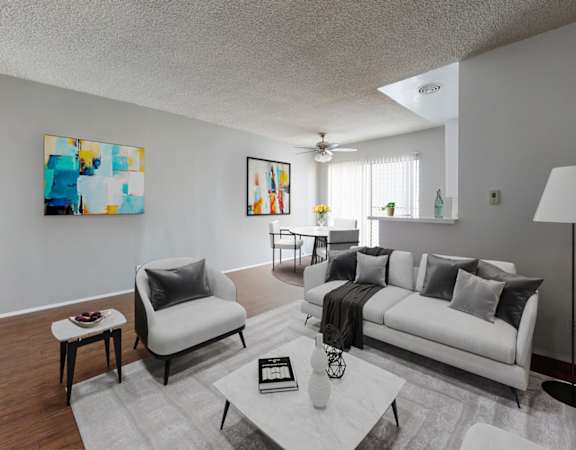 A modern living room with a white couch and a painting on the wall.