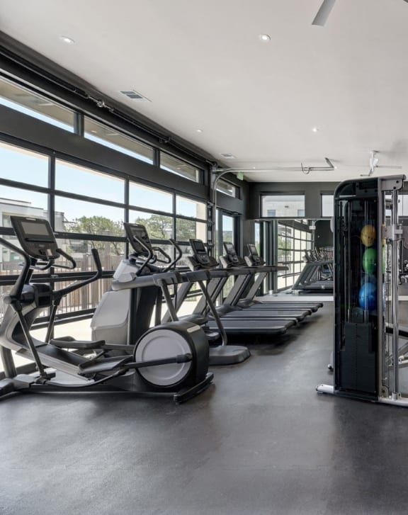 a gym with weights and cardio equipment and windows