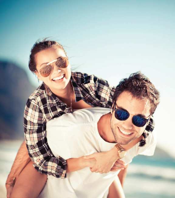 A man is giving a piggyback ride to a woman on a beach at Rose Apartments, Los Angeles, CA