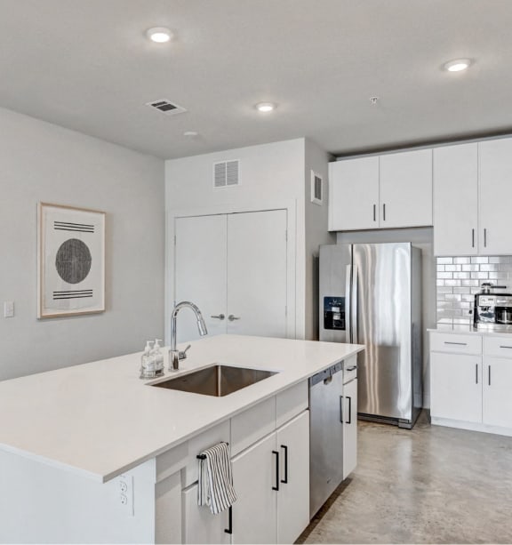 an open kitchen with white cabinets and a white island with a sink