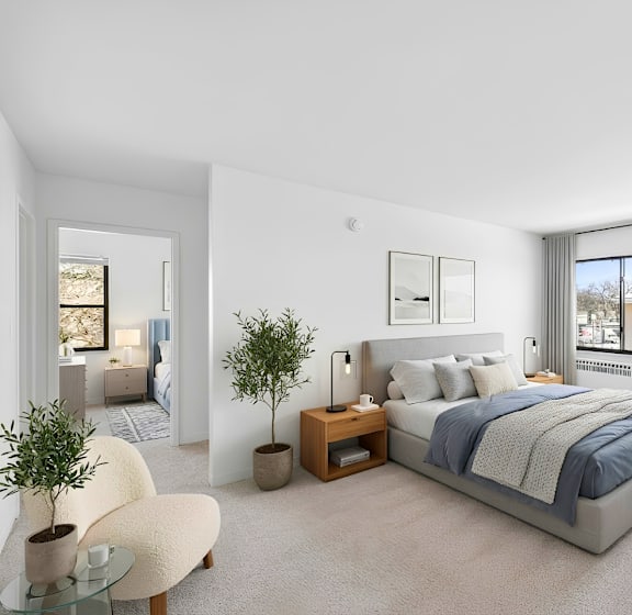 A bedroom with a large bed, a chair, and a plant.