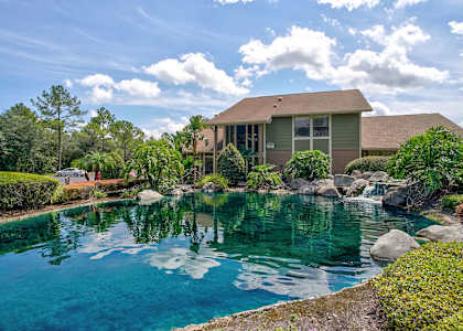 a house with a pond and water feature in front of it at Whisper Lake Apartments, Winter Park, 32792