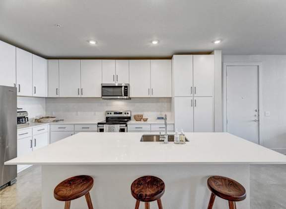 a kitchen with a white counter top and three stools