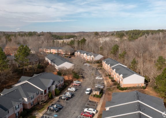 A bird's eye view of a parking lot with cars and apartment buildings.