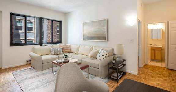 A living room with a couch, chair, and a painting on the wall.