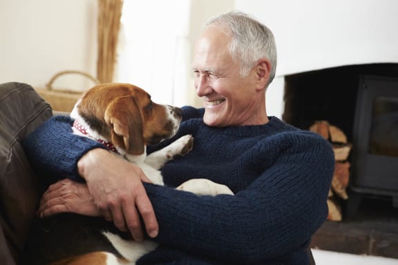 a man sitting on a couch with his dog at Legacy Commons at Signal Hills 55+ Apartments, West St. Paul, MN, 55118