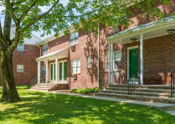 the front of a brick house with green doors and a lawn and tree at Nottingham Manor Apartments, Montvale, New Jersey
