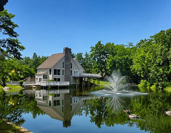 A house is reflected in the water of a pond.