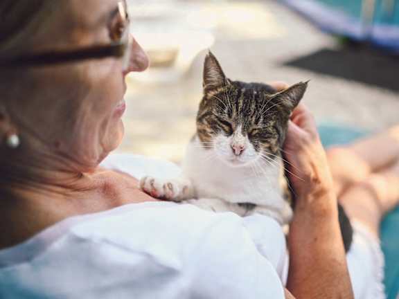 A woman is holding a cat with a white and brown coat.at The Rosalyn | Affordable 55+ Apartments in Bloomington, Minnesota, 55420